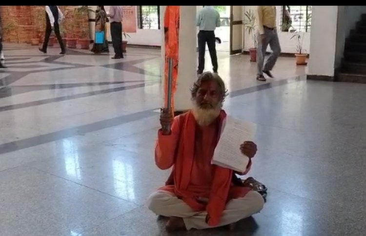 बढ़ी दाढ़ी, गले में माला और गेरुआ वस्त्रधारी पहुंचा कलेक्ट्रेट और पोर्च पर धरने पर बैठ गया, हाथ में झंडा भी था